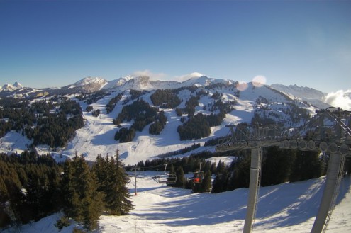 Blue skies over snowy ski slopes in Les Gets, with chairlift and skiers in the foreground – Weather to ski – Snow forecast, 21 January 2022