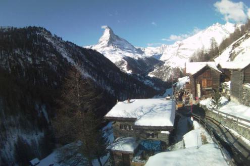 Blue skies over Findeln in Zermatt, Switzerland, with a snowy panoramic mountain view towards the Matterhorn with chalet style buildings in the foreground – Weather to ski – Snow forecast, 4 February 2022