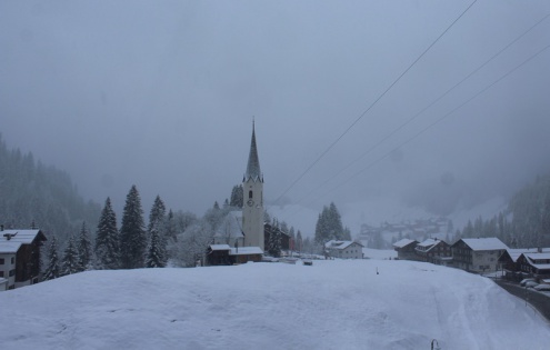Snow falling in Schrӧcken, Austria, with view of the village and its church – Weather to ski – Snow forecast, 1 April 2022