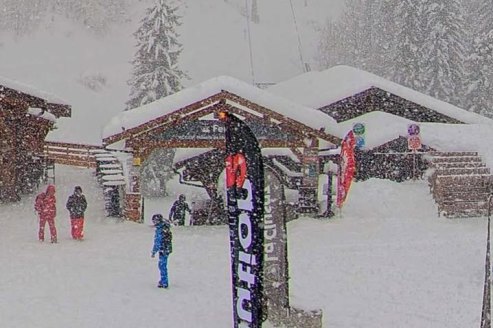 Snow falling over the ski slopes, skiers and chalet-style building in La Clusaz ski resort in France – Weather to ski – Snow report, 30 January 2026
