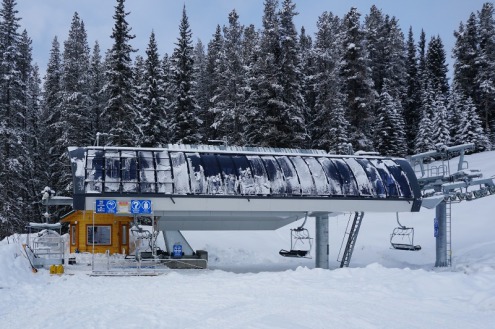 Deep snow, and snow-covered trees behind a chair lift station in Lake Louise, Canada – Weather to ski – Snow report, 3 February 2022
