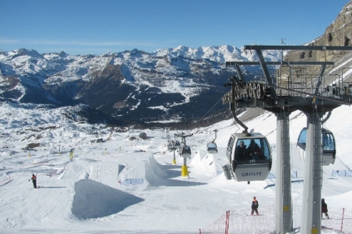 View over the snow park in Madonna di Campliglio, Italy, looking towards the valley below with panoramic mountain views and gondola lift to the right – Weather to ski – Half Term Snow report, 10 February 2022