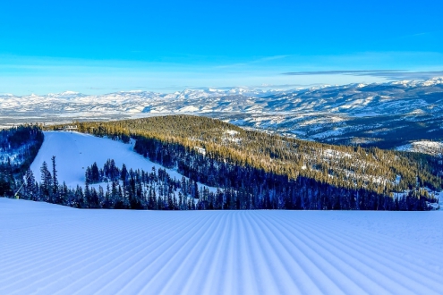 View of perfectly groomed pistes in Winter Park, Colorado, with endless panoramic views into the distance of snow-covered mountains and blue skies above – Weather to ski – Half Term Snow report, 10 February 2022