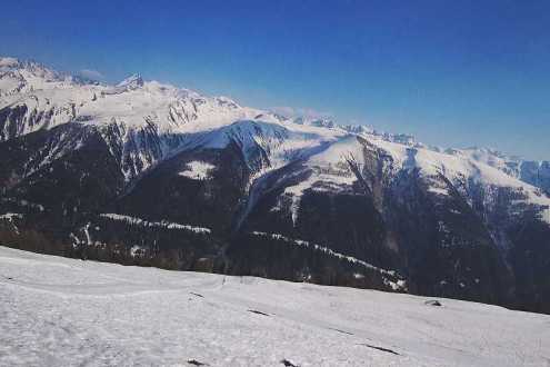 Snow-covered slopes and panoramic mountain view across the valley with blue skies above in Bellwald, Switzerland – Weather to ski – Snow report, 25 March 2022