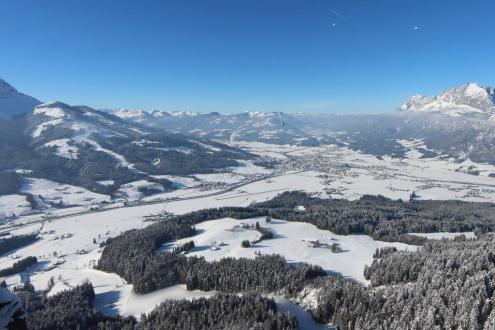 Blue skies and hot air balloons over the snow-covered valley in St Johann in Tirol, Austria – Weather to ski – Snow forecast, 29 January 2023
