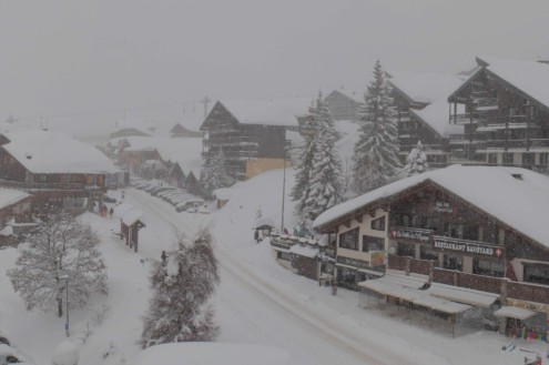 Heavy snow falling on the already deep snow-covered streets and chalet-style buildings in Les Saisies, France – Weather to ski – Snow report, 19 February 2026