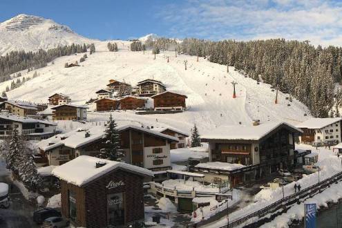 Blue skies over the snow-covered buildings and pistes in Lech, Austria – Weather to ski – Snow report, 15 December 2023