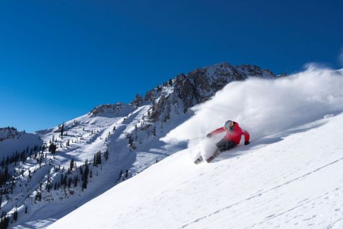 Blue skies over steep snow-covered slope with skier skiing in powder in Snowbird, Utah, USA – Weather to ski – Snow report, 15 December 2023