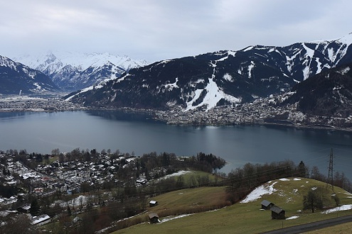 View over the lake in Zell-am-See, Austria with snow on the ski slopes but little around the lakeside – Weather to ski – Snow report, 24 December 2023