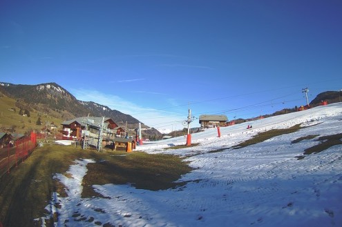 Blue skies over the ski slopes with patchy snow cover in Flumet near Megève, France – Weather to ski – Snow report, 24 December 2023
