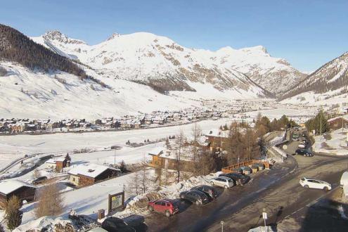 Blue skies over the snow-covered slopes of Livigno with view over the resort in the valley – Weather to ski – Snow report, 30 December 2023