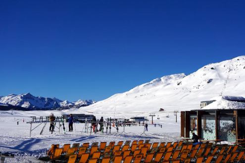 Deep blue skies over the pistes in Baqueira Beret Spain, looking across rows of deckchairs with skiers standing by a ski rack and a restaurant to the right of the deckchairs – Weather to ski – Snow report, 3 February 2022
