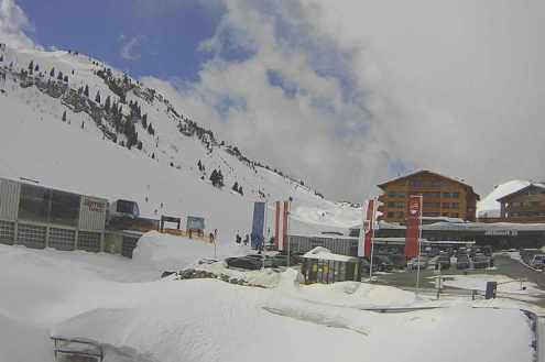 View of ski slopes, lift station and carpark with snow on the ground and cloudy skies in the ski resort of Warth-Schröcken, Austria – Weather to ski – Snow forecast, 25 February 2022