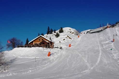 View of the L’Aventure mountain restaurant to the left of the Lutins run, below the Poutran gondola mid-station, in the Oz-en-Oisans ski area, with drag lift to the right, and blue skies above on 21 December 2021 – Weather to ski - Our blog: Alpe d’Huez –