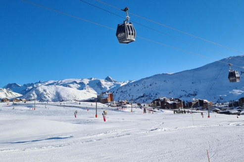 Sunny view over the snowy nursery slopes above the Bergers sector of Alpe d’Huez with the Rifnel Express gondola in the foreground, and the resort centre in the background on 17 December 2021 - Weather to ski – Our blog: Alpe d’Huez – one of the best all-