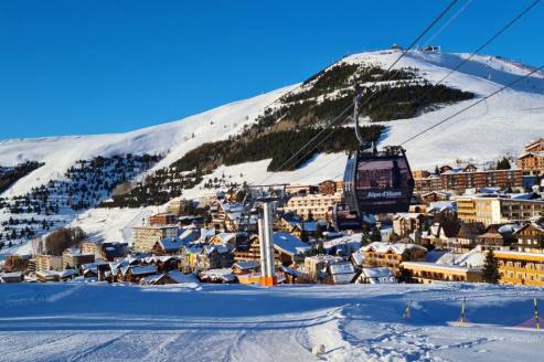 View of ski slope at the bottom of the resort of Alpe d’Huez, France, with the Alpe Express gondola in the foreground, on 17 December 2021 - Weather to ski – Our blog: Alpe d’Huez – one of the best all-round ski resorts in the Alps?