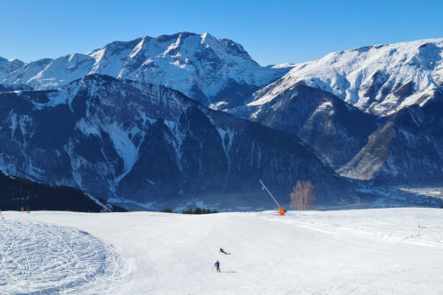 Blue skies and panoramic scenery over a wide ski run in Auris-en-Oisans with skier in the distance, on 18 December 2021 - Weather to ski – Our blog: Alpe d’Huez – one of the best all-round ski resorts in the Alps?