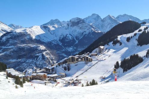 View of the village of Auris-en-Oisans from the blue Le Col ski run, with blue skies and panoramic mountain views, on 18 December 2021 - Weather to ski – Our blog: Alpe d’Huez – one of the best all-round ski resorts in the Alps?