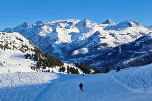 Snowy south-east facing ski slope in Auris-en-Oisans with blue skies and panoramic mountain view towards the ski area of Les 2 Alpes, on 18 December 2021 – Weather to ski – Our blog: Alpe d’Huez – one of the best all-round ski resorts in the Alps?