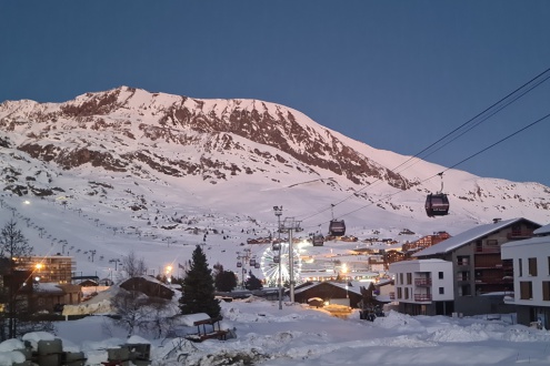 View of the Bergers sector and its lit up ferris wheel during sunset over the snowy mountains, from the balcony of the Chalet des Neiges apartments in Alpe d’Huez – Our blog: Alpe d’Huez – one of the best all-round ski resorts in the Alps?
