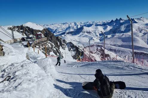 View over the very top of the Sarenne black run from the Pic Blanc in Alpe d’Huez with snowboarder in the foreground on 21 December 2021 – Weather to ski - Our blog: Alpe d’Huez – one of the best all-round ski resorts in the Alps?