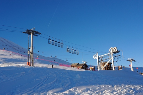 View towards the ski slopes of the Stade sector of the Alpe d’Huez ski area, with blue skies above, and the resort’s bucket lift (or ‘panier’) in the foreground on 21 December 2021 - Weather to ski – Our blog: Alpe d’Huez – one of the best all-round ski r