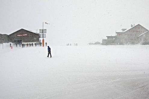 Snowy and windy weather in Engelberg, Switzerland, with people standing in the foreground and buildings in the background – Weather to ski – Today in the Alps, 31 January 2022
