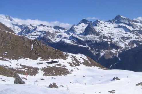 Panoramic mountain view with blue skies over snow-covered pistes and the valley in the Monte Rosa region in Italy – Weather to ski – Snow forecast, 25 February 2022