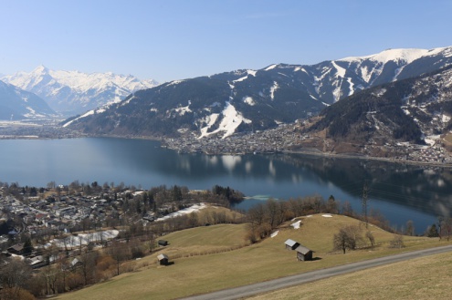 Blue skies above the lake at Zell-am-See Austria, with snow-covered slopes behind the village – Weather to ski – Today in the Alps, 21 March 2022