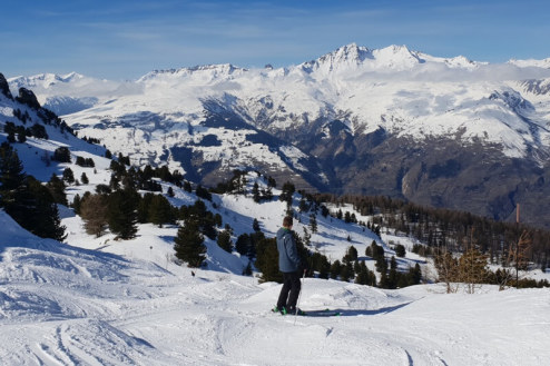 Skier standing on the Malgovert ski slope in Les Arcs, France, looking across the mountain to the valley below - Weather to ski – Our blog: Top 5 pistes in Les Arcs
