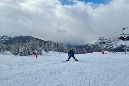 Skier standing on the snow-covered Renard piste in Les Arcs, France, with chairlift above the piste to the right - Weather to ski – Our blog: Top 5 pistes in Les Arcs