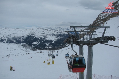 View down the ski slopes towards the valley in Madonna di Campiglio, Italy, with mid- to high-level cloud above the gondola in the foreground – Weather to ski – Today in the Alps, 19 December 2022