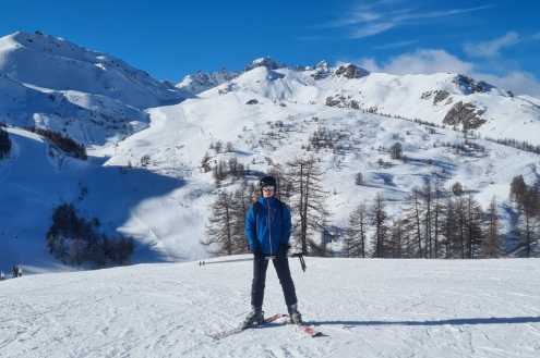 Blue skies above the snow-covered slopes in Serre Chevalier, France with skier in the foreground – Weather to ski – Today in the Alps, 6 January 2023
