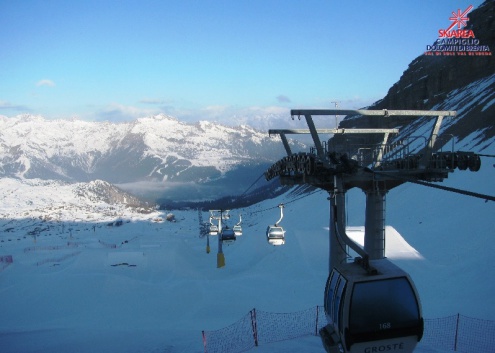 Sun shining above the ski slopes of Madonna di Campiglio, with gondola ski lift in the foreground – Weather to ski – Today in the Alps, 24 February 2023