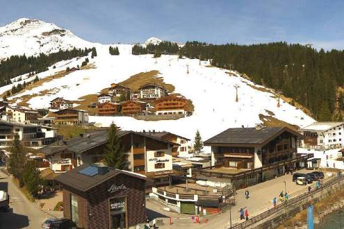 Blue skies over spring-likes ski slopes and the village in Lech, Austria – Weather to ski – Today in the Alps, 10 April 2023