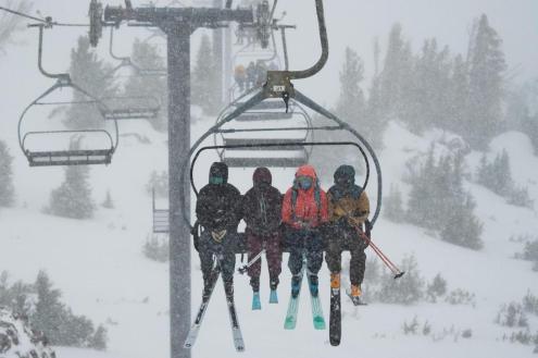 Snow falling on skiers on chairlift, with snow-covered mountain terrain and trees below in Mammoth, California, on 9 November 2021 – Weather to ski – Who got the most snow in North America in 2021-22?