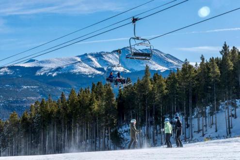 Blue skies over the ski slopes in Breckenridge, USA, with skiers standing below a chair-lift – Weather to ski – Snow report, 1 December 2023