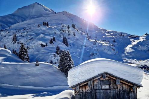 Blue skies above a snow-covered Alpine style building in Lech, Austria – Weather to ski – Today in the Alps, 18 December 2023