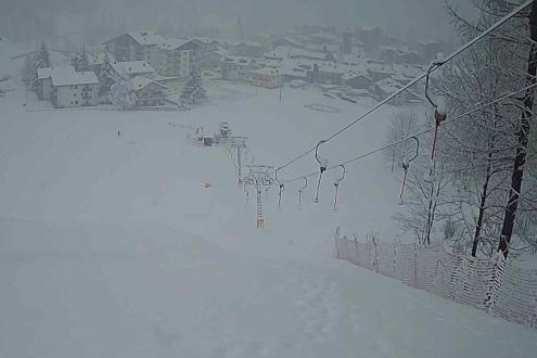 Heavy snow falling on the ski slopes of Prali, Italy, with view down the slopes over the chairlift and down to the village below – Weather to ski – Today in the Alps, 3 March 2024