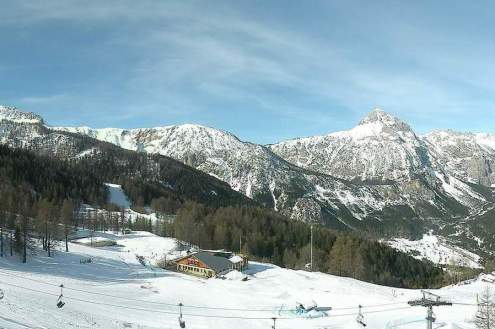 Good snow cover on the ski slopes of Bardonecchia, Italy, with panoramic views of blue skies over the mountains and valley below, and skilift in the foreground – Weather to ski – Today in the Alps, 14 March 2024