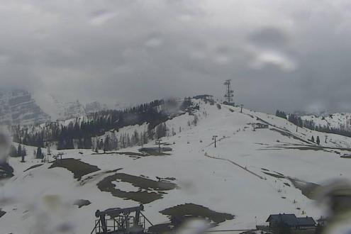 Rain falling on the ski slopes of Lofer, Austria, with patchy snow and view of ski lifts – Weather to ski – Today in the Alps, 21 March 2024