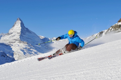 View of skier carving in front of the Matterhorn on the slopes of Zermatt ski resort, Switzerland, for Weather to Ski's snow reliability guide
