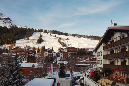 Mostly sunny skies above the snow-covered ski slopes beyond the resort centre of Lech, Austria – Weather to ski – Today in the Alps, 1 January 2026
