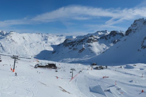 Sunny skies over snow-covered pistes with skiers and mountain buildings in Tignes ski resort, France – Weather to ski – Today in the Alps, 13 January 2026