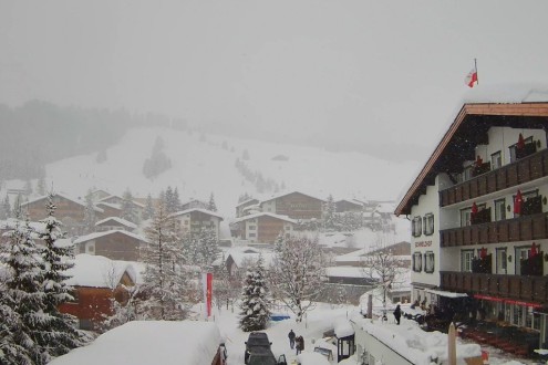 Snow falling over the traditional mountain buildings in the centre of Lech, Austria – Link to Weather to ski's full "Today in the Alps" report on weather and snow in the Alps on 21 February 2026
