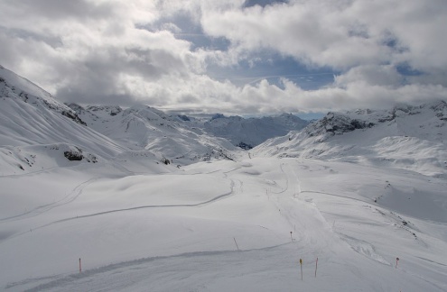 Cloudy skies with the sun trying to break through above the snow-covered ski slopes at altitude in Lech, Austria – Link to Weather to ski's full "Today in the Alps" report on weather and snow in the Alps on 22 February 2026