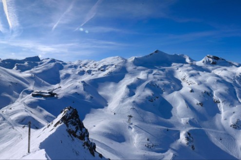 Blue skies above the snow-covered mountains and ski slopes in Les 2 Alpes, France – Weather to ski – Today in the Alps, 24 February 2026