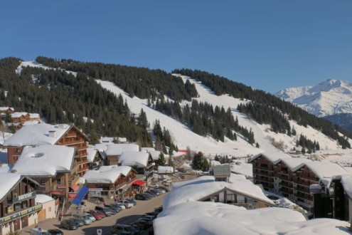Blue skies over the snow-topped buildings in Les Saisies, with ski slopes beyond – Weather to ski – Snow report, 26 February 2026