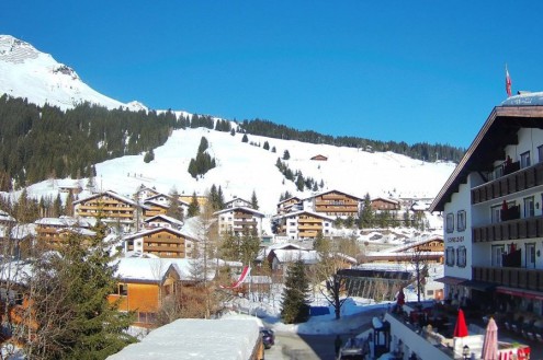 Sunny skies over the ski slopes and traditional buildings in the centre of Lech, Austria – Link to Weather to ski's full "Today in the Alps" report on weather and snow in the Alps on 27 February 2026