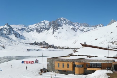 Blue skies over Tignes, France, and the snow-topped building with the “Tignes” sign in front of the lake in Tignes Le Lac – Weather to ski – Today in the Alps, 16 April 2026